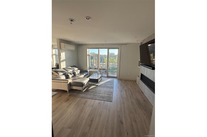 Living room with light wood-type flooring and an AC wall unit