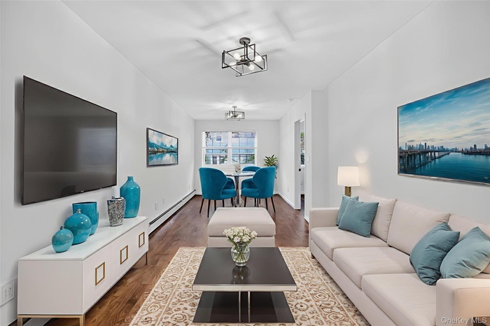 Living area featuring wood finished floors, a baseboard heating unit, and a chandelier
