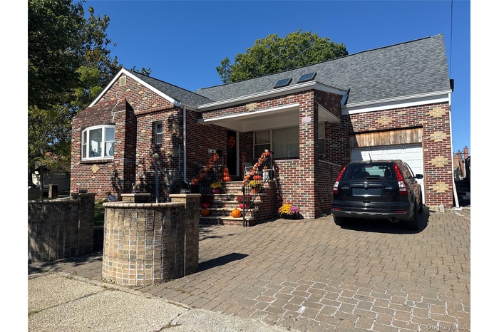 View of front of home featuring brick siding, a shingled roof, an attached garage, and a porch
