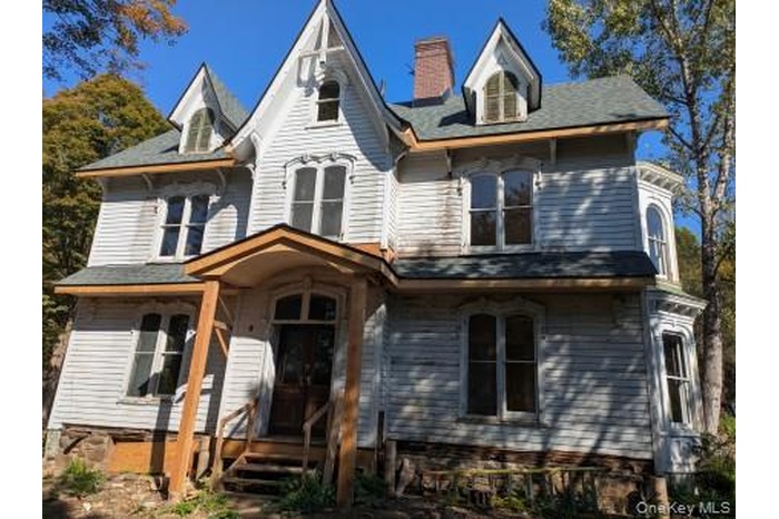 Victorian home featuring covered porch and a chimney