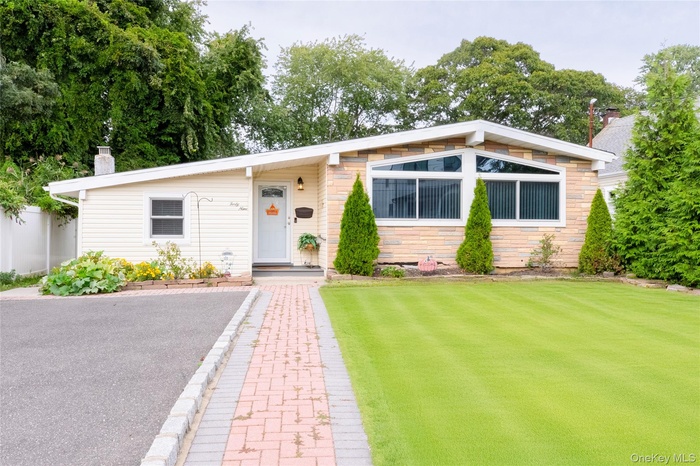View of front of home featuring a chimney, a front yard, and stone siding