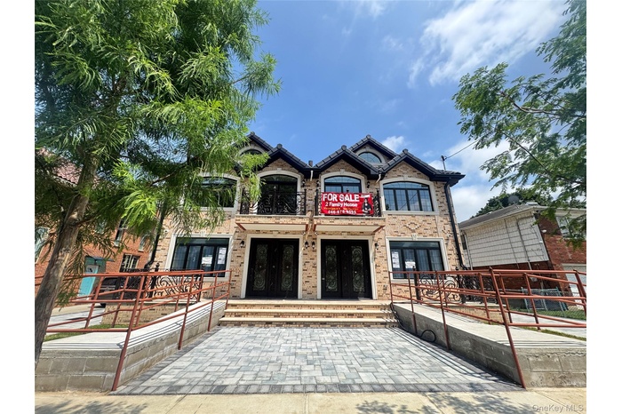 View of front facade featuring french doors, brick siding, and a balcony