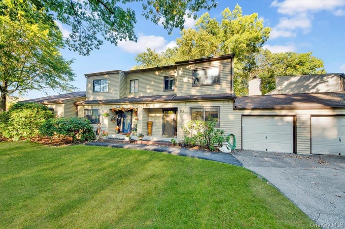 View of front of home with a front lawn, an attached garage, and driveway