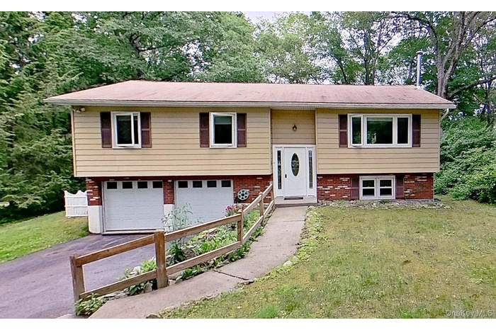 Split foyer home featuring asphalt driveway, an attached garage, and a front yard