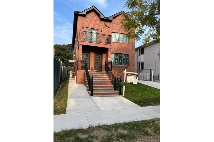 View of front of property featuring brick siding, a balcony, and stairway