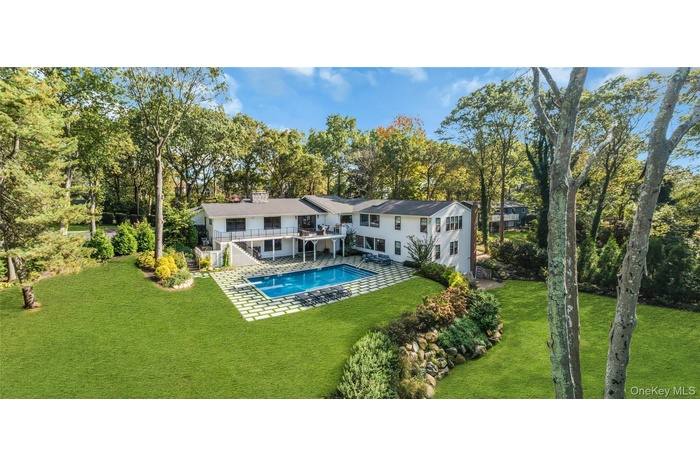 Rear view of house featuring a patio area, view of wooded area, and a yard