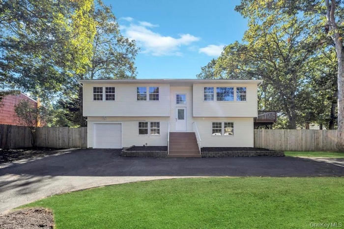 Bi-level home with driveway, a deck, and a garage