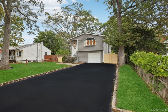 View of front facade featuring an attached garage and asphalt driveway