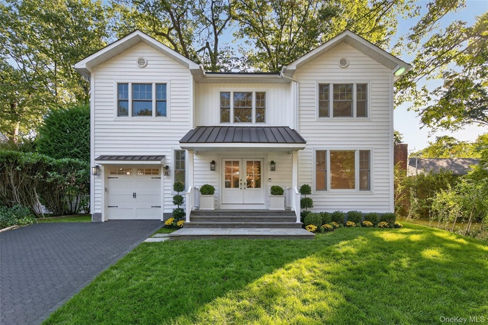 View of front of house featuring a porch, a front lawn, asphalt driveway, an attached garage, and french doors