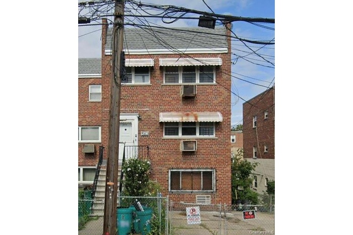 View of front of house featuring a gate, a fenced front yard, brick siding, and a chimney