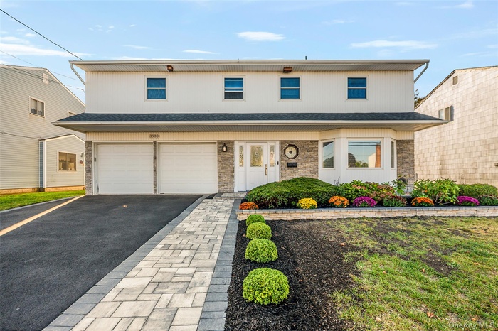 Traditional-style house featuring asphalt driveway, an attached garage, stone siding