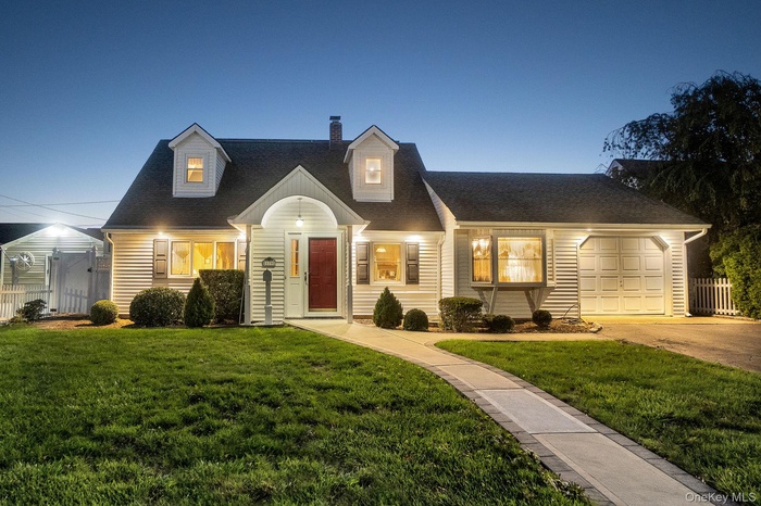New england style home featuring a chimney, roof with shingles, an attached garage, and driveway