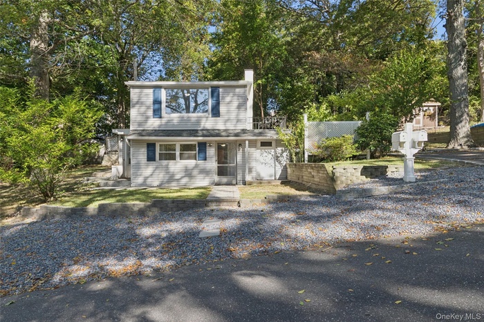 View of front facade with a chimney and view of wooded area