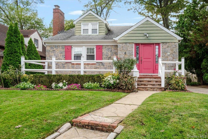 View of front facade featuring stone siding, a chimney, and a shingled roof