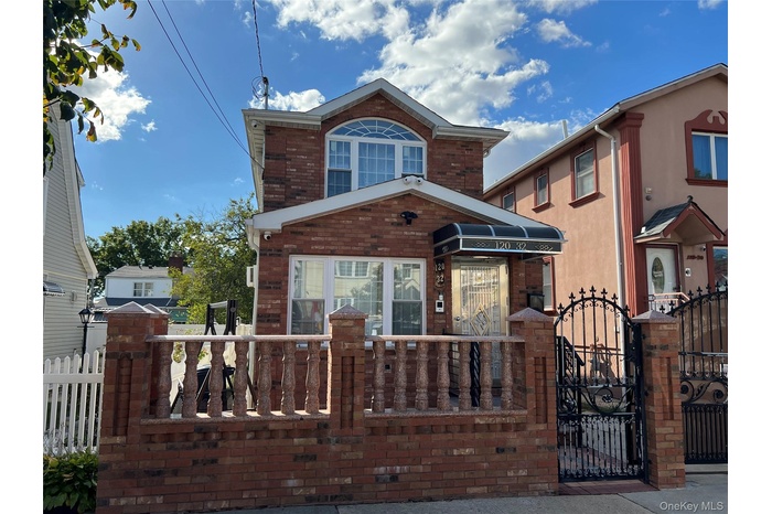 Traditional home featuring a fenced front yard, brick siding, and a gate