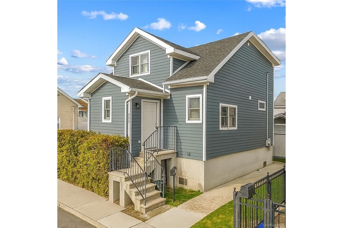 View of front of home featuring roof with shingles and a gate