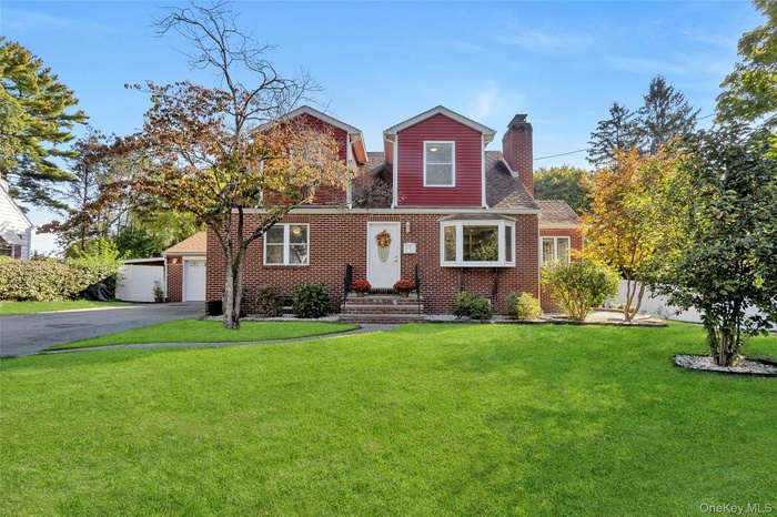 View of front of home featuring a chimney, brick siding, a garage, driveway, and a shingled roof
