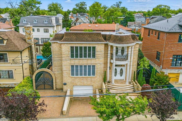 View of front facade with a balcony, an attached garage, decorative driveway, and a residential view