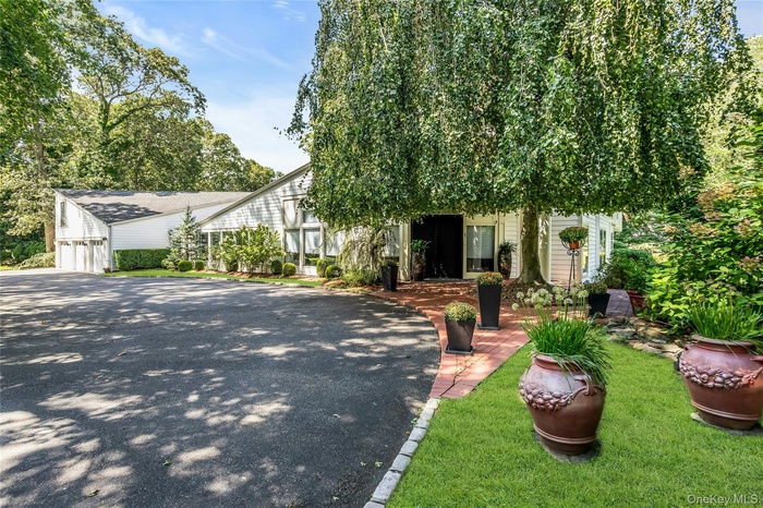 View of front of property featuring a garage, asphalt driveway, and a front yard