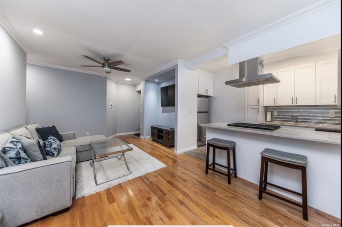 Living room with crown molding, light wood-type flooring, a ceiling fan, and recessed lighting