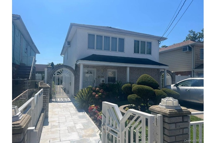 View of front of home with a fenced front yard, a gate, and brick siding