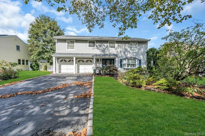 Traditional-style house featuring a front yard, asphalt driveway, an attached garage, and a porch