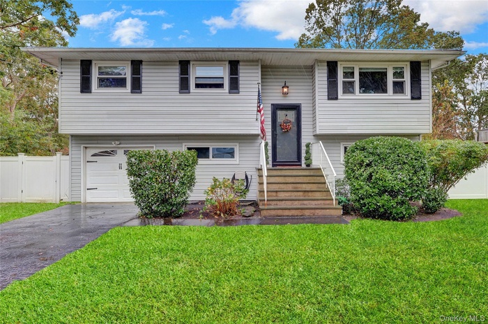 Bi-level home featuring a garage and asphalt driveway