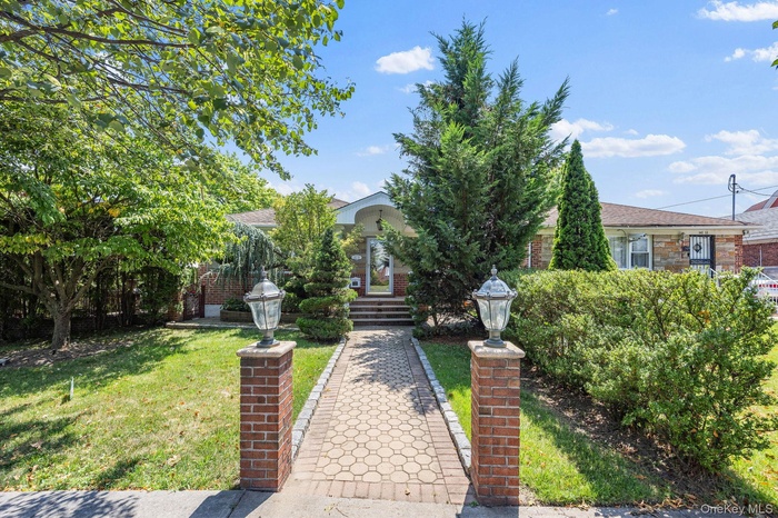 View of property hidden behind natural elements featuring a front yard, brick siding, and a shingled roof