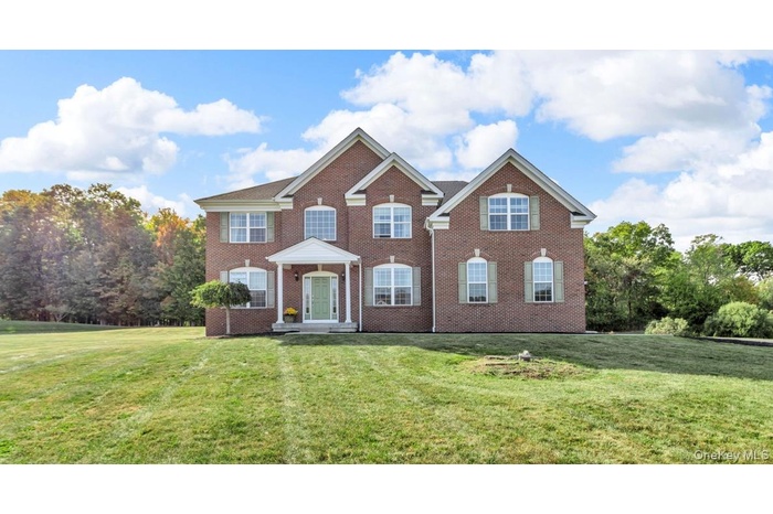 Colonial home with a front lawn, brick siding