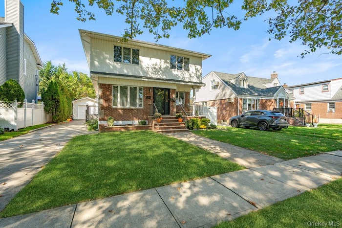 View of front of house with an outbuilding and brick siding
