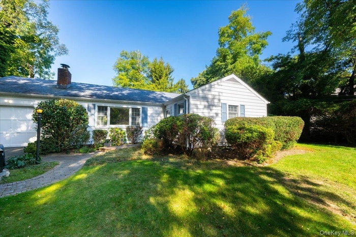 View of front of home featuring a front lawn, a chimney, and an attached garage