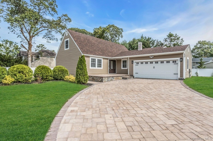 View of front of house featuring a front yard, an attached garage, decorative driveway, a chimney, and a shingled roof
