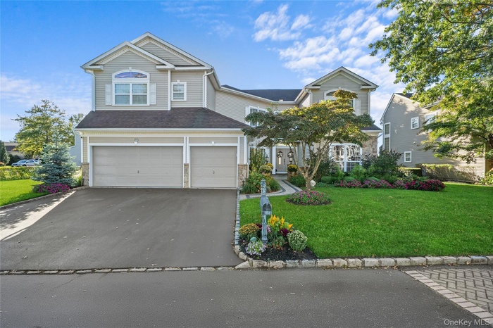 View of front of home with driveway, a front lawn, an attached garage, and stone siding