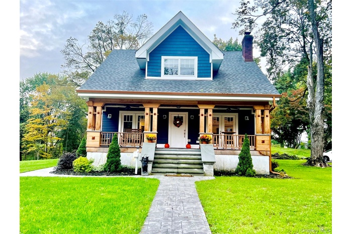 View of front of house featuring a front lawn, a porch, and roof with shingles