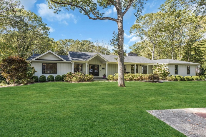 Single story home with a front yard, roof with shingles, a porch, and board and batten siding