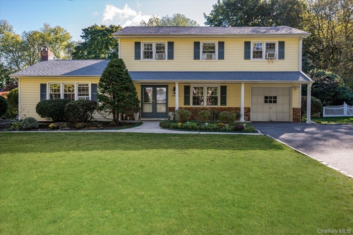 Traditional-style home with driveway, a front yard, a chimney, an attached garage, and french doors