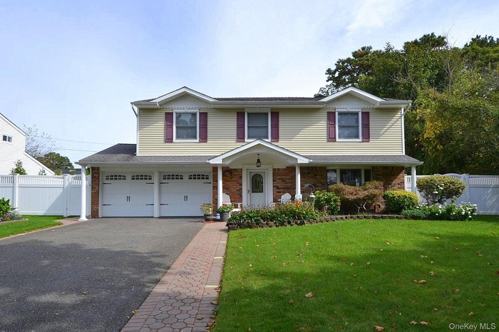 Traditional-style home with driveway, brick siding, a garage, roof with shingles, and a porch