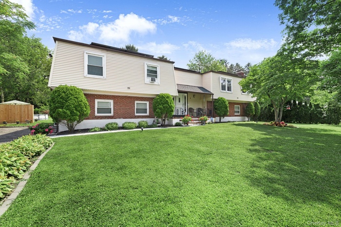 Bi-level home with covered porch, a front yard, and brick siding