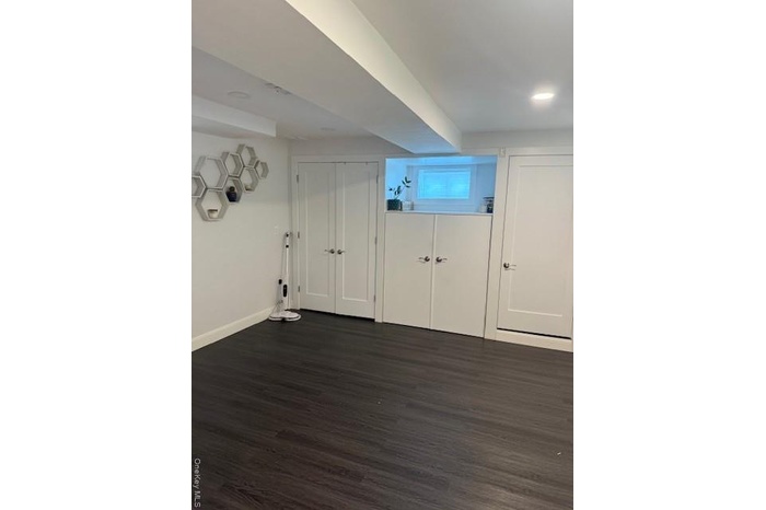 Basement with dark wood-style floors and baseboards