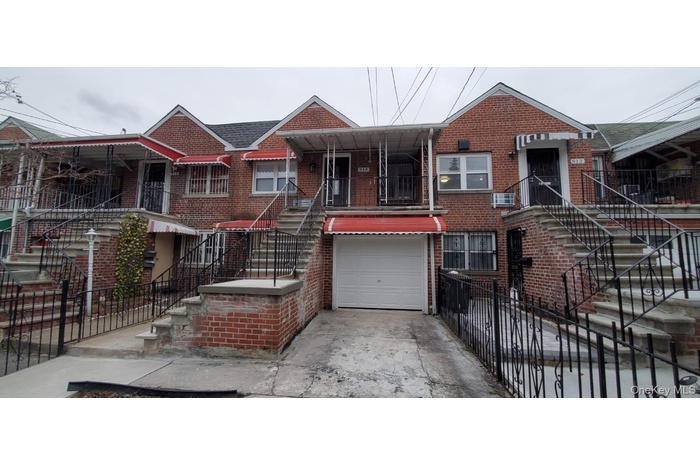 View of front facade with brick siding, a garage, stairway, and concrete driveway