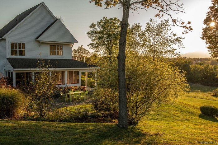 View of side of property featuring a yard, covered porch, and roof with shingles