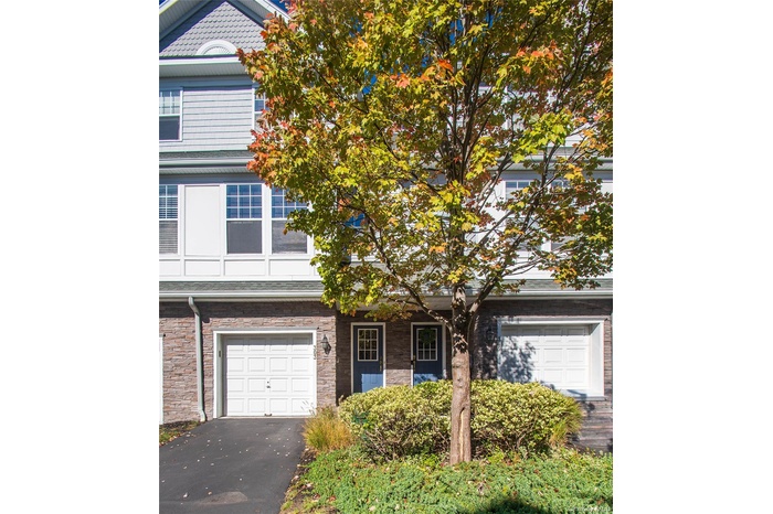 View of front of home with stone siding, asphalt driveway, a garage, and a porch