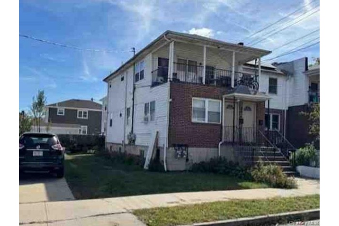 View of front of home featuring a front lawn and a balcony
