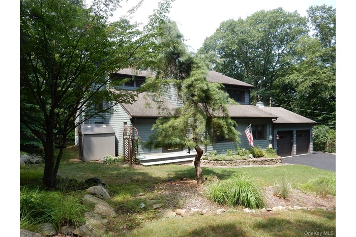 Obstructed view of property with a garage, roof with shingles, and a wooden deck