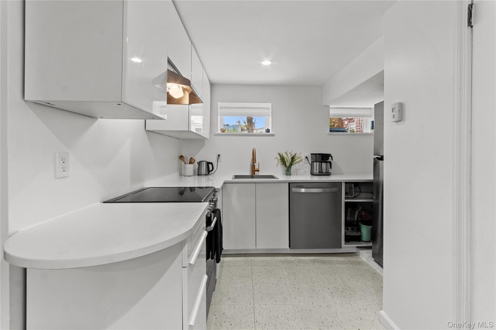 Kitchen featuring stainless steel appliances, white cabinets, recessed lighting, light floors, and modern cabinets