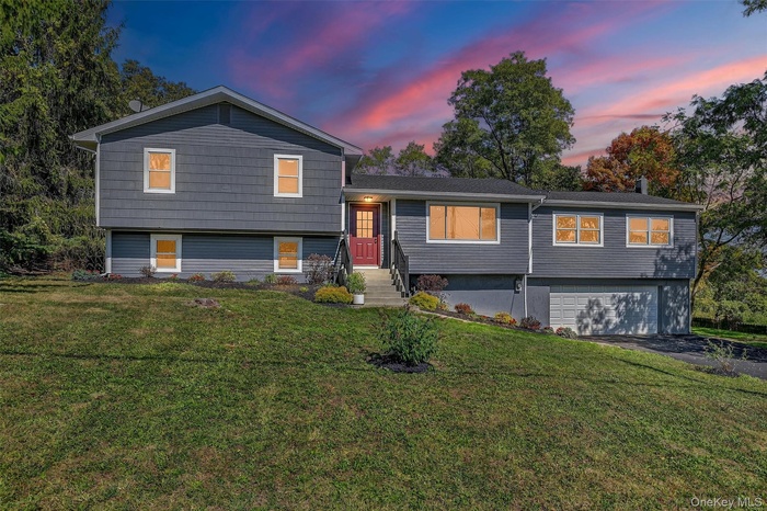 Split level home featuring a lawn, an attached garage, and driveway