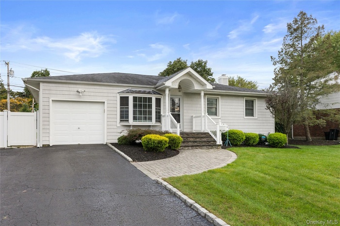 Ranch-style home with a front yard, asphalt driveway, a chimney, and an attached garage