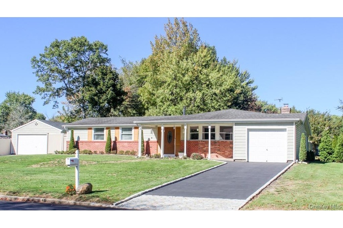 Ranch-style house with a porch, a front lawn, a garage, driveway, and a chimney
