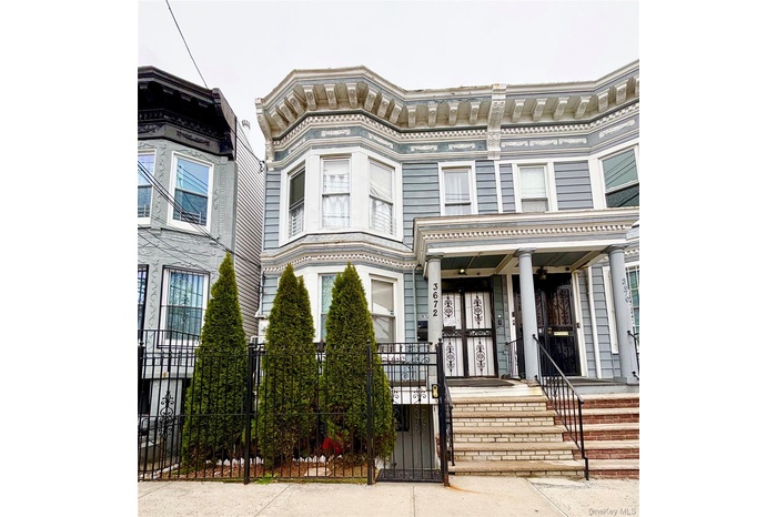 Italianate-style house featuring a porch and a fenced front yard