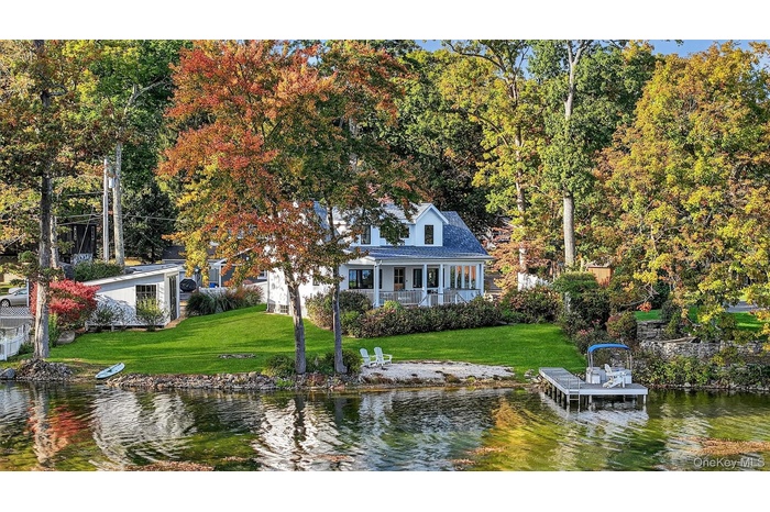 Dock area with a water view, a lawn, and a porch